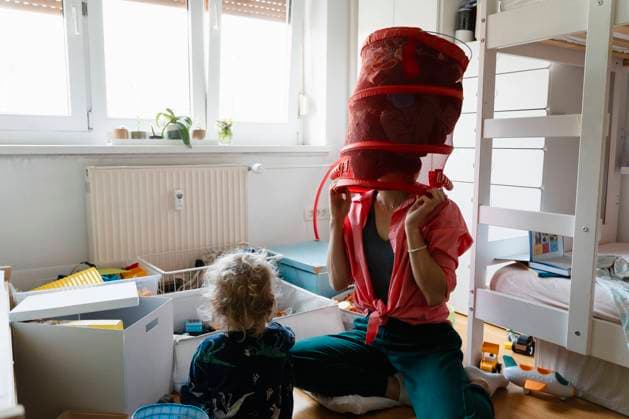 IMAGO Creative, Frühling, Frühjahrsputz Mother holding laundry basket upside down and playing with boy at home model released, Symbolfoto property released, NDEF02010