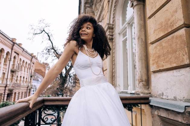 Creative Highlights Symbolbilder Eine junge afrikanische Frau in einem eleganten weißen Kleid und Schmuck steht auf dem Balkon eines Retro-Hauses. Vintage klassischen Stil der Architektur A young African woman in an elegant white dress and jewelry stands on the balcony of a retro house. Vintage classic style of architecture. An attractive black girl smiles and looks at the street ,model released, Symbolfoto Copyright: xZoonar.com DashaxPetrenkox 22303716 ,model released, Symbolfoto ,property released