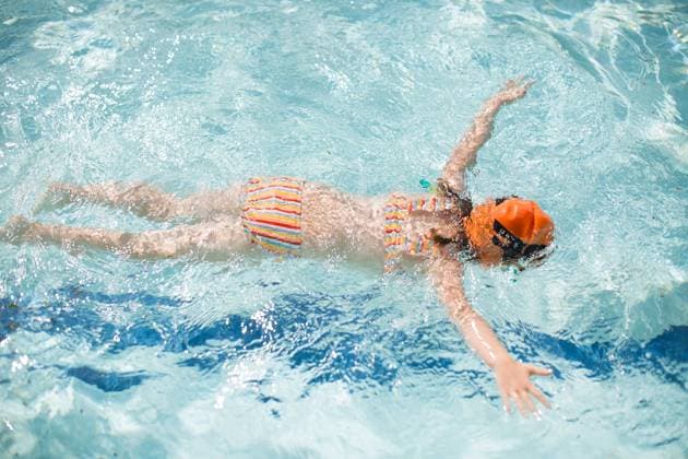 Creative Highlights Symbolbilder 5 year old girl floating on stomach in pool with swim cap Baltimore, Maryland, United States CR_HHXY241125-1300856-01 ,model released, Symbolfoto