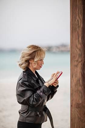 Creative Highlights Symbolbilder Businesswoman standing against sea background using smart phone Çe?me, ?zmir, Türkiye R_THNZ241125A-1584854-01 ,model released, Symbolfoto