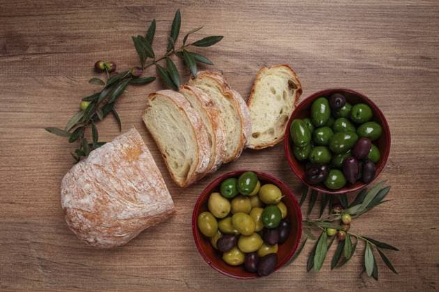 Eine Mischung aus Oliven, Sorten von Chalkidiki, Verdi giganti und Kalamata, in einer Schale, mit geschnittenem Ciabata Brot, Ansicht von oben, ohne Personen A mixture of olives, varieties of Halkidiki, Verdi giganti and Kalamata, in a bowl, with sliced ciabata bread, top view, no people Copyright: imageBROKER GalinaxDidebashvili ibxgai11831348.jpg