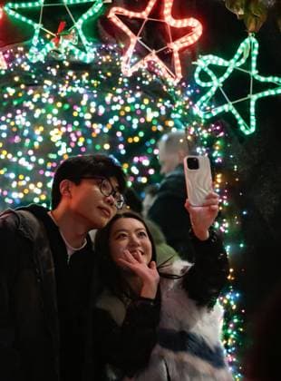 (241128) -- VANCOUVER, Nov. 28, 2024 -- People pose for a selfie in front of the Christmas lights during the Lights of Hope lighting ceremony in Vancouver, British Columbia, Canada, Nov. 27, 2024. Lights of Hope is one of Vancouver s largest annual Christmas fundraiser, showcasing over 200,000 colourful lights illuminating St. Paul s Hospital. (Photo by Liang Sen Xinhua) CANADA-VANCOUVER-CHRISTMAS-LIGHTS OF HOPE LinxWei 
