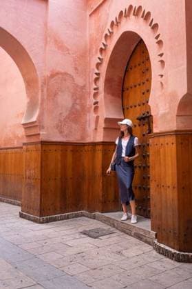 Creative Highlights Symbolbilder Woman in casual attire stands by ornate wooden door of historic architecture in Marrakech, Morocco. 27468710 ,model released, Symbolfoto RECORD DATE NOT STATED