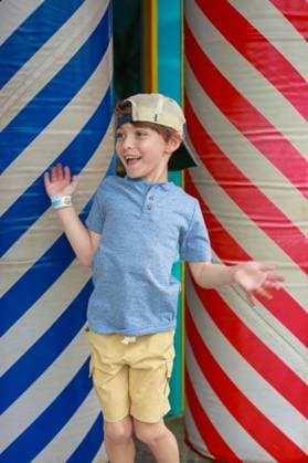 Creative Highlights Symbolbilder A Caucasian joyful young boy wearing a cap and wristband standing between colorful striped pillars with excitement expression in Orlando, Florida 26359243 ,model released, Symbolfoto RECORD DATE NOT STATED