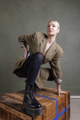 783449156 Frau in modischer Kleidung posiert auf einer Holzkiste vor grünem Hintergrund, Fotoshooting Woman in fashionable clothes posing on a wooden box in front of a green background, photo shoot Copyright: imageBROKER RonaldxMitterer ibxrmr11829809.jpg ,model released, Symbolfoto ,property released