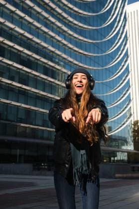 Creative Highlights Symbolbilder 783449156 Woman wear headphones point at you and smile in front of a building Madrid, Community of Madrid, Spain CR_CRVI241202-1589072-01 ,model released, Symbolfoto