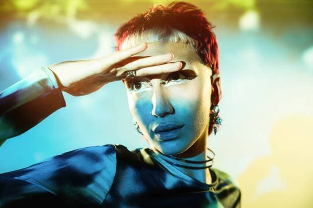 Creative Highlights Symbolbilder 783449156 A futuristic woman featuring striking blue face paint and vibrant red hair, positioned against a vivid, abstract backdrop Model Released ManuelRuiz_ID25552_738447_003 Copyright: xManuelxRuizx