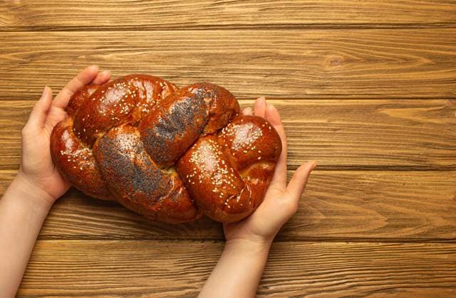 Weibliche Hände halten frisch gebackenes Challah-Brot mit Mohn- und Sesamkörnern, Draufsicht auf rustikalen Holzhintergrund, traditionelle festliche jüdische Küch Female hands holding freshly baked Challah bread covered with poppy and sesame seeds, top view on rustic wooden background, traditional festive Jewish cuisine. Copyright: xZoonar.com OlenaxYeromenkox 22313048