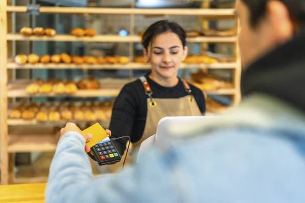 Rückansicht eines lateinamerikanischen Mannes, der mit einer Kreditkarte und einem berührungslosen Terminal in einer handwerklichen Bäckerei bezahlt Rear view of a latin man paying with credit card and contact less terminal in an artisan bakery Copyright: imageBROKER UnaixHuizi ibxuhu11892641.jpg ,model released, Symbolfoto ,property released