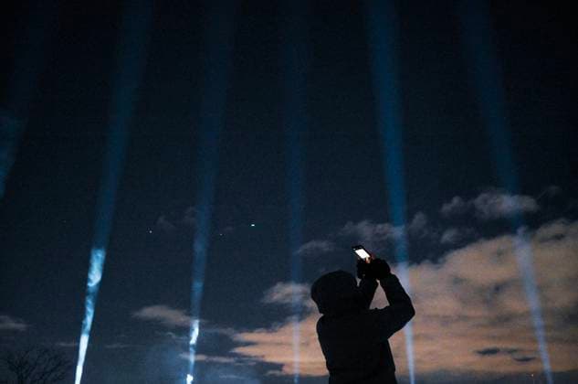 December 6, 2024, Montreal, Pq, Canada: A person takes photographs of beams of light projected into the sky during a vigil to honour the victims of the 1989 Polytechnique massacre in Montreal, Friday, December 6, 2024. Today marks the 35th anniversary of the shooting rampage that left 14 women dead. Montreal Canada  - ZUMAc35_ 20241206_zaf_c35_080 Copyright: xGrahamxHughesx