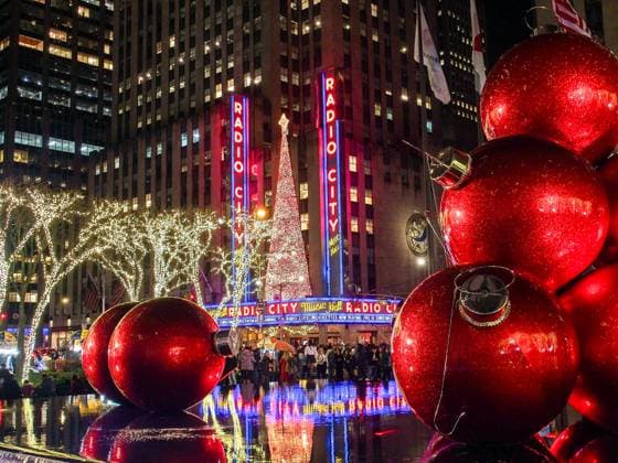 December 17, 2024, New York, New York, USA: Red life like tree decorations reflect in water with the Radio City Music Hall decked out with Christmas tree in the background along 5th Avenue in NYC. New York USA - ZUMAo116 20241217_znp_o116_033 Copyright: xBiancaxOterox