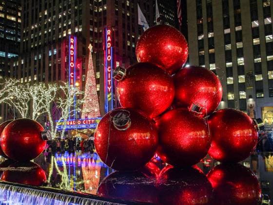December 17, 2024, New York, New York, USA: Red life like tree decorations reflect in water with the Radio City Music Hall decked out with Christmas tree in the background along 5th Avenue in NYC. New York USA - ZUMAo116 20241217_znp_o116_036 Copyright: xBiancaxOterox