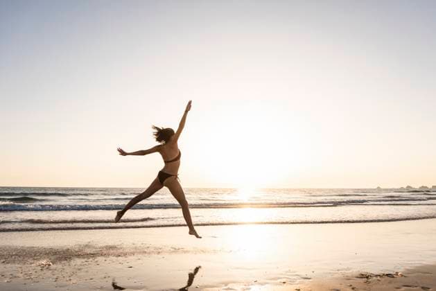 Young woman jumping for joy on the beach model released, Symbolfoto, UUF15143
