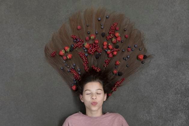 Creative Highlights Symbolbilder Portrait of girl lying on floor with eyes closed and fruits on hair model released, Symbolfoto, PSTF00218