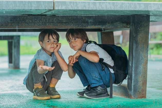 Smiling boys crouching under table in rain model released, Symbolfoto, ANAF04331