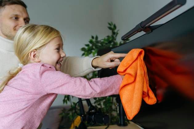 IMAGO Creative, Frühling, Frühjahrsputz Smiling girl with father cleaning computer monitor at home model released, Symbolfoto property released, NSTF00375