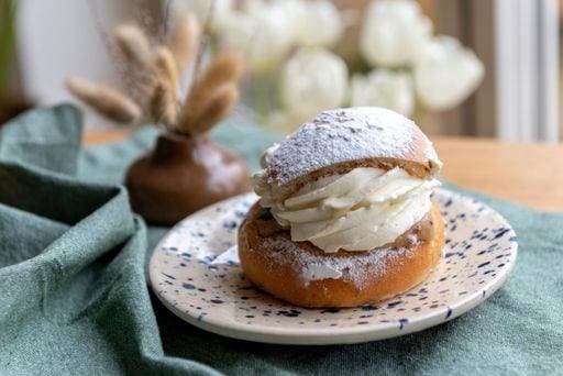 Typical Swedish semla with sweet cream on te blue textile. 27982875 RECORD DATE NOT STATED
