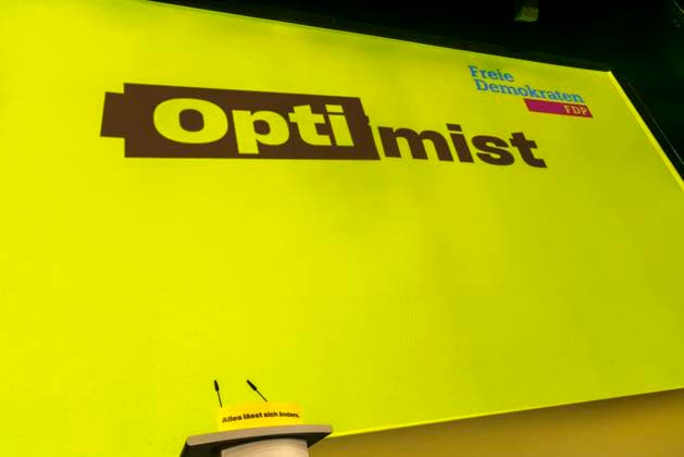 Dreikönigstreffen 2025 der FDP in Stuttgart. Leeres Rednerpult. Großplakat mit der Aufschrift Optimist. 06.01.2024: Stuttgart, Baden-Württemberg, Deutschland. *** Epiphany meeting 2025 of the FDP in Stuttgart Empty lectern Large poster with the inscription Optimist 06 01 2024 Stuttgart, Baden Württemberg, Germany
