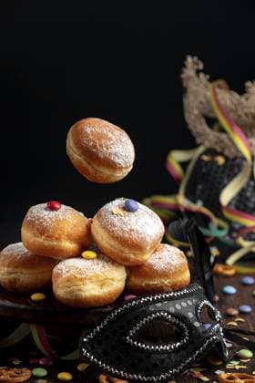 Berliner, Krapfen mit Puderzucker und Smarties neben einer schwarzen Maske, Fasching Berliners, doughnuts with icing sugar and Smarties next to a black mask, carnival Copyright: imageBROKER LucasxSeebacher ibxlse12103539.jpg