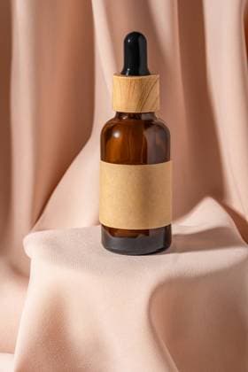 IMAGO Creative, Naturkosmetik A stylish amber glass dropper bottle with a wooden cap rests gracefully on soft beige fabric Perfect for cosmetics or essential oils Elegant and minimalist design Model Released Ikvyatkovskaya_ID25902_748246_006 Copyright: xIkvyatkovskayax