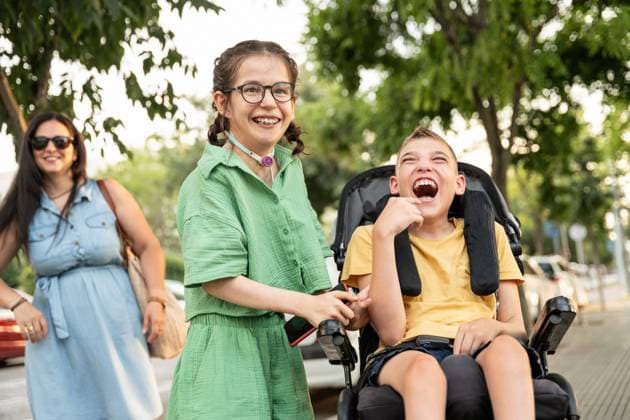 A joyful family outing shows a girl with a tracheostomy and a boy with cerebral palsy in a supportive, loving environment, celebrating inclusivity and resilience. Model Released ManuelRuiz_ID26011_750574_074 Copyright: xManuelxRuizx