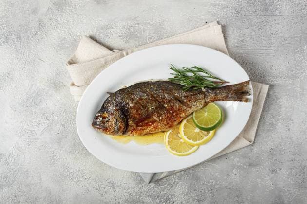 Gebackene Goldbrasse, im Ofen, gebratene Goldbrasse, mit Gewürzen und Kräutern, auf einem weißen Teller, von oben, hausgemacht, ohne Personen Baked dorado fish, in the oven, fried dorado, with spices and herbs, on a white plate, top view, homemade, no people Copyright: imageBROKER xDidebashvili ibxgai12125018.jpg