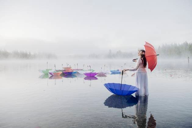 Creative Highlights Symbolbilder A woman in a white dress stands in shallow water, holding a red umbrella surrounded by colorful umbrellas floating on the serene lake, Wildcat Lake, WA, USA WA USA sape00447 Copyright: xConnectxImagesx ,model released