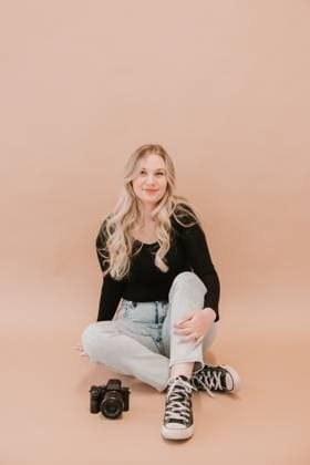 Young female photographer sitting with a camera on a beige background Detroit, Michigan, United States R_YCQU250121D1-1634366-01 ,model released, Symbolfoto