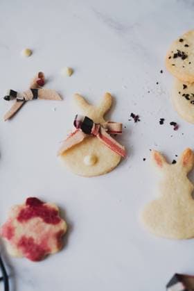 Top view of homemade Easter bunny cookies intricately decorated with hibiscus tea for a natural red hue, scattered across a marble surface. Model Released CamilaMacedo_ID26013_750672_001 Copyright: xCamilaxMacedox RECORD DATE NOT STATED