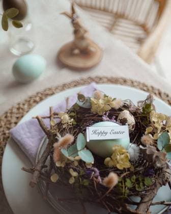 IMAGO Creative, Ostern, Bräuche, Osterbrunch Top view of an elegantly arranged Easter table setting featuring naturally dyed eggs nestled in a decorative nest with spring flowers and a tag reading Happy Easter. Model Released CamilaMacedo_ID26016_750692_006 Copyright: xCamilaxMacedox RECORD DATE NOT STATED