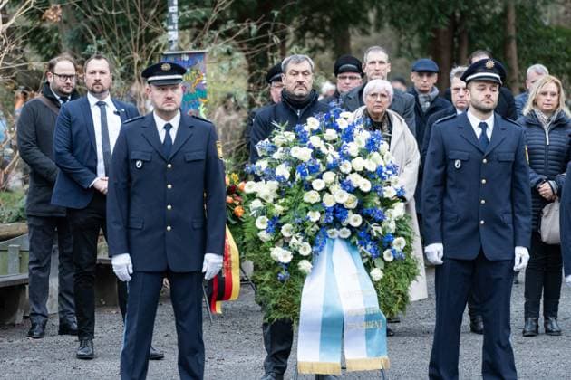 Aschaffenburg, Bavaria, Germany - January 26, 2025: Memorial service wreath-laying ceremony in Schöntal Park after knife attack in Aschaffenburg. Markus Söder and Claudia Roth stand behind a magnificent wreath with blue and white flowers, flanked by police officers. Together they show dignity and respect during the memorial service. *** Gedenkfeier Kranzniederlegung im Schöntal Park nach Messerangriff in Aschaffenburg. Markus Söder und Claudia Roth stehen hinter einem prächtigen Kranz mit blauen und weißen Blumen, flankiert von Polizeibeamten. Gemeinsam zeigen sie Würde und Respekt während der Gedenkfeier.