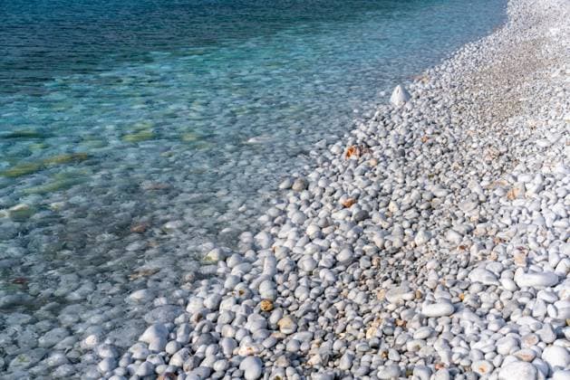 Creative Highlights World Pebble beach detailed view with turquoise water Diros, Greece CR_UGOUSD250120-1613578-01