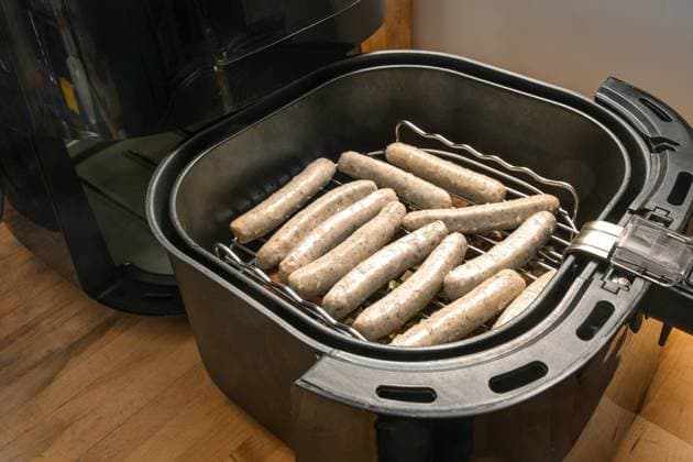 Rohe Schweinewürstchen, in Deutschland Nürnberger Rostbratwurst genannt, liegen in einer Heißluftfritteuse auf einem Gestell, um mit wenig Öl gebraten zu werden, ausgewählter Schwerpunkt Raw small pork sausages, in Germany called Nuremberg rostbratwurst, lying in a hot air fryer on a rack to be fried with less oil, selected focus, narrow depth of field Copyright: xZoonar.com MarenxWinterx 22695600
