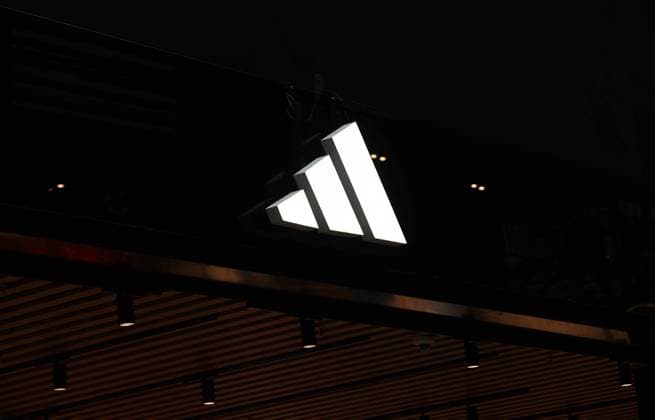25.01.2025, Deutschland, Sachsen, Sportartikelhersteller, Logo vor dunklem Hintergrund über einem Adidas Store, Adidas plant in seiner Konzernzentrale in Herzogenaurach einen Stellenabbau trotz guter Umsätze im letzten Jahr, Deutschland Copyright: xD.xKerlekin SnowfieldxPhotographyx SF250125AdidasD