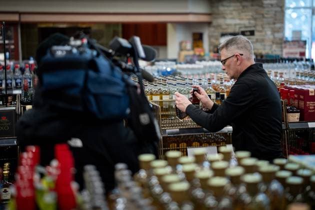 February 2, 2025, Vancouver, Bc, CANADA: A B.C. Liquor Store employee demonstrates removing bottles of American whiskey for media before a news conference in Vancouver, B.C., Sunday, Feb. 2, 2025. Vancouver CANADA  - ZUMAc35_ 20250202_zaf_c35_116 Copyright: xEthanxCairnsx