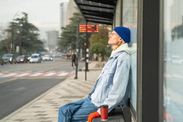 IMAGO Creative, Gesellschaft, Leisure Sickness Müder Mann mit geschlossenen Augen wartet auf den Transport an der Bushaltestelle am Morgen nach der Nachtarbeit. Tired sleepy young man sitting at bus stop with cup coffee, relaxing in warm sunlight with eyes closed. Early morning of exhausted student guy after sleepless night waiting for transport to college. ,model released, Symbolfoto Copyright: xZoonar.com DmitriixMarchenkox 22743678 ,model released, Symbolfoto ,property released