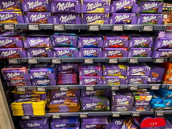 Symbolfoto - Milka Schokolade - Regale im Supermarkt Disconter mit verschiedenen Sorten Milka Alpenmich Schoholade in lilla Papier gehült mit dem Logo der Milka Kuh. Der Name ist eine Kombination der beiden Hauptzutaten Milch und Kakao. Der Kakaopreis steigt und steigt. Und das macht unsere geliebte Schoggi teurer Der US-Produzent Mondelez verkleinert zahlreiche Sorten.Drastische Preiserhöhung bei einer der bekanntesten Schokoladen-Marken Verbraucherinnen und Verbraucher müssen für Schokolade der bekannten Marke Milka derzeit vielerorts tiefer in die Tasche greifen Mondelez International ist ein börsennotierter US-amerikanischer Lebensmittelkonzern mit Sitz in Chicago, Illinois, der überwiegend auf Markenprodukte in den Bereichen Sna