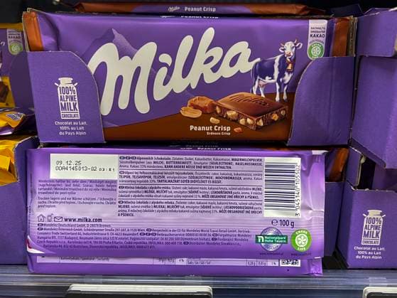 Symbolfoto - Milka Schokolade - 2 Tafeln Milka Alpenmich Schoholade mit dem jetzigen Geicht von 100 g im Regal beim Supermarkt in lilla Papier gehült mit dem Logo der Milka Kuh. Der Name ist eine Kombination der beiden Hauptzutaten Milch und Kakao. Der Kakaopreis steigt und steigt. Und das macht unsere geliebte Schoggi teurer Der US-Produzent Mondelez verkleinert zahlreiche Sorten.Drastische Preiserhöhung bei einer der bekanntesten Schokoladen-Marken Verbraucherinnen und Verbraucher müssen für Schokolade der bekannten Marke Milka derzeit vielerorts tiefer in die Tasche greifen Mondelez International ist ein börsennotierter US-amerikanischer Lebensmittelkonzern mit Sitz in Chicago, Illinois, der überwiegend auf Markenprodukte in den