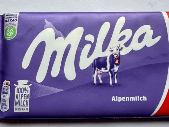 Symbolfoto - Milka Schokolade - Das Milka Logo mit der Lilla Kuh beim Supermarkt Discounter in lilla Papier gehült mit dem Logo der Milka Kuh. Der Name ist eine Kombination der beiden Hauptzutaten Milch und Kakao. Der Kakaopreis steigt und steigt. Und das macht unsere geliebte Schoggi teurer Der US-Produzent Mondelez verkleinert zahlreiche Sorten.Drastische Preiserhöhung bei einer der bekanntesten Schokoladen-Marken Verbraucherinnen und Verbraucher müssen für Schokolade der bekannten Marke Milka derzeit vielerorts tiefer in die Tasche greifen Mondelez International ist ein börsennotierter US-amerikanischer Lebensmittelkonzern mit Sitz in Chicago, Illinois, der überwiegend auf Markenprodukte in den Bereichen Snacks und Süßwaren spez