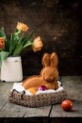 An easter bunny cookie in a wicker basket with colorful eggs and tulips in a rustic setting. 28840575 RECORD DATE NOT STATED