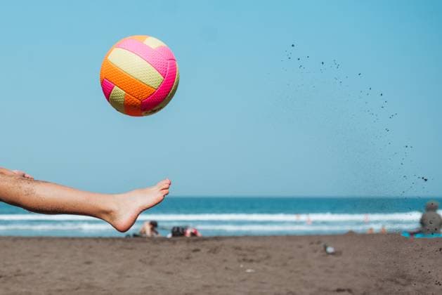 Close up of boy s leg kicking soccer ball on sandy beach, enjoying family vacation. Close up of boy s leg kicking soccer on a sandy beach, enjoying a family vacation. model released