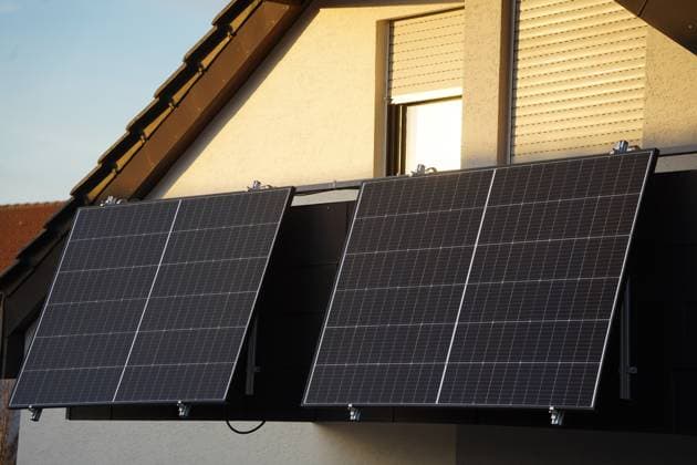 Balkonkraftwerk von einer Dachgeschosswohnung. Abendsonne unterm Dach - Dunkelheit auf dem Solarmoul Eine Dachgeschosswohnung mit Balkon und grossen Solarmodulen. Die Abendsonne scheint noch mit goldenem Licht auf die Fenster und Balkontür, die Solarpanele liegen aber schon im Schatten Copyright: xZoonar.com YvenxDienstx 22664269