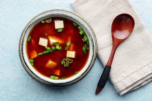 Tofu-Suppe, japanische Küche. Miso-Suppe mit Bohnenquark und grünen Zwiebeln Tofu soup, Japanese cuisine. Miso soup with bean curd and green onions, a staple of Asian cuisine, overhead flat lay shot, with a spoon Copyright: xZoonar.com KaterinaxSolovyevax 22799407