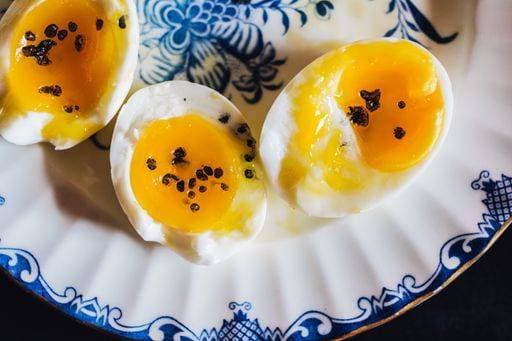 soft boiled egg halves with peppercorns on fancy blue and white plate 20024139 RECORD DATE NOT STATED