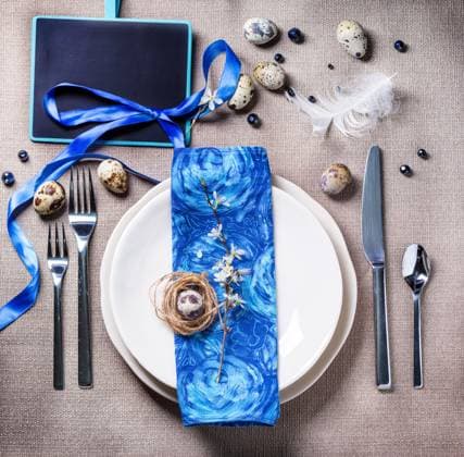 Gedeckter Ostertisch Easter table setting with blue textile napkin, blossom branch and quail eggs. Top view. Copyright: xZoonar.com NatashaxBreenx 22811532