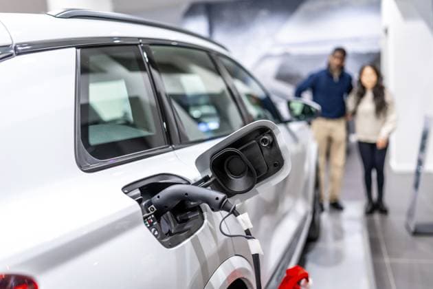 Ein Ehepaar betrachtet ein aufladbares Elektroauto in einem Autohaus und setzt auf nachhaltige Mobilität Couple looking at a charging electric car in a dealership, embracing sustainable transportation Copyright: imageBROKER UnaixHuizi ibxuhu12460357.jpg ,model released, Symbolfoto ,property released