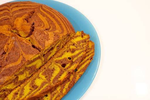 A slice of cake with a blue plate on a white background. The cake is cut into pieces and has a zebra print on it 23751262 RECORD DATE NOT STATED