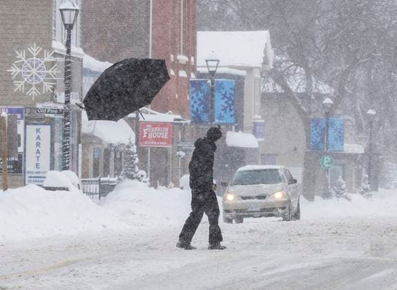 (250217) -- MISSISSAUGA, Feb. 17, 2025 -- A pedestrian s umbrella is broken and blown away as he crosses a street in Mississauga, the Greater Toronto Area, Canada, on Feb. 16, 2025. (Photo by Xinhua) CANADA-THE GREATER TORONTO AREA-WINTER STORM ZouxZheng 