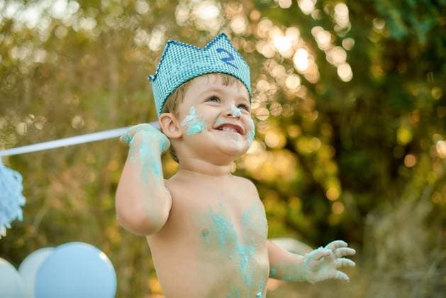 Creative Highlights Symbolfotos A joyful toddler boy wearing a blue crown celebrates a cake smash, covered in blue frosting during a sunny outdoor party Model Released GabrielTrujillo_ID21879_641076_029 Copyright: xx