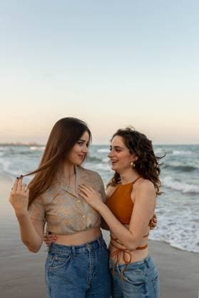 Creative Highlights Symbolfotos Young girlfriends embracing each other while standing on sandy beach near waving sea at sundown looking at each other Model Released LeoPastor_ID18057_543216_006 Copyright: xLeoxPastorx